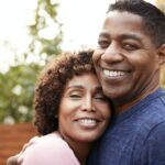 Happy middle aged black couple embracing smile to camera, close up